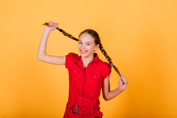 Pretty teenager girl smiling on camera looking cheerful on a yellow background. Positive emotions - Foto, afbeelding