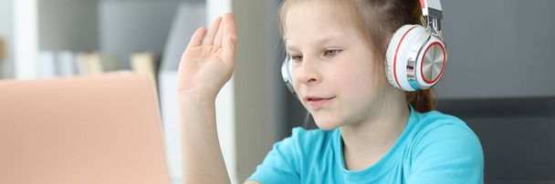 Kulaklıklı, dizüstü bilgisayara bakan 6 yaşında tatlı bir kız. - Fotoğraf, Görsel