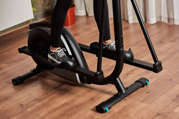 Vrouw benen training op smart elliptical trainer binnen thuis - Foto, afbeelding