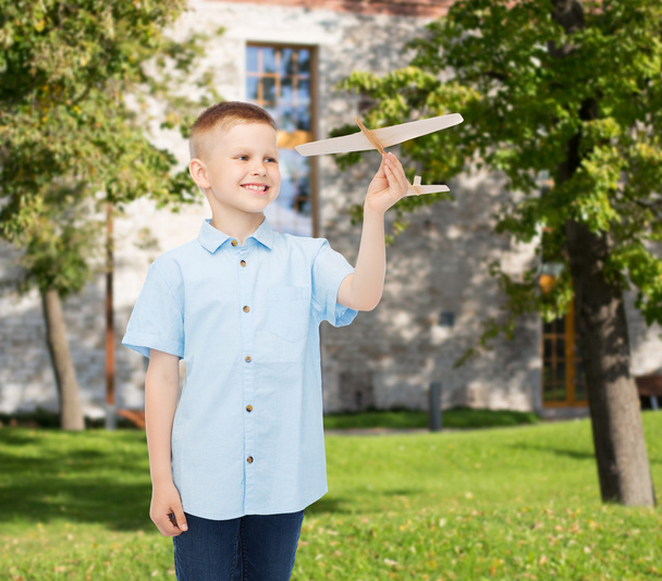 smiling little boy holding a wooden airplane model - Foto, Bild