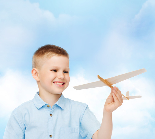 笑顔の坊やを抱きかかえて離さない木製の飛行機モデル - 写真・画像