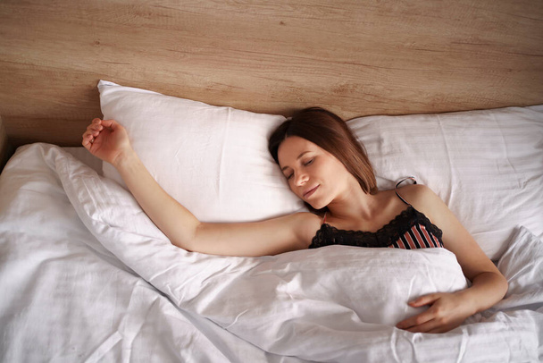 Привлекательная молодая женщина хорошо спит в постели - Фото, изображение
