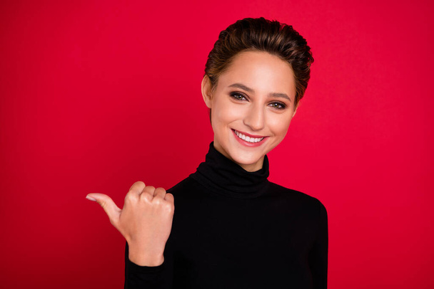 Photo of cheerful young happy positive woman point finger empty space thumb isolated on red color background - Photo, Image