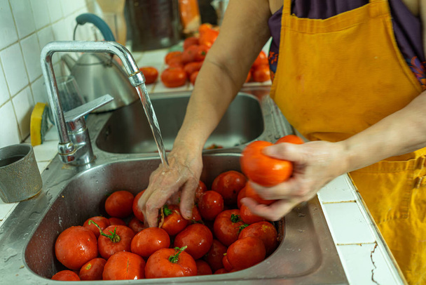 A view of hands washing tomatoes in the kitchen sink - Foto, afbeelding
