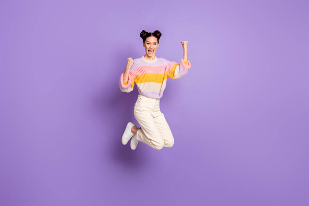 Full length photo of girlish lucky young lady dressed striped sweater jumping rising fists isolated violet color background - Foto, Imagen