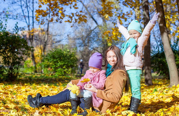 weinig cute meisjes en jonge moeder in herfst park - Foto, afbeelding