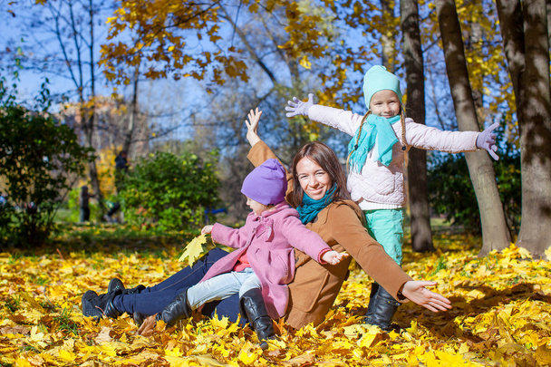 Маленькі милі дівчата і молода мати в осінньому парку розважаються
 - Фото, зображення