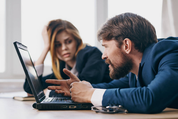 zakenman en vrouw zittend aan een bureau met een laptop communicatie ambtenaren - Foto, afbeelding