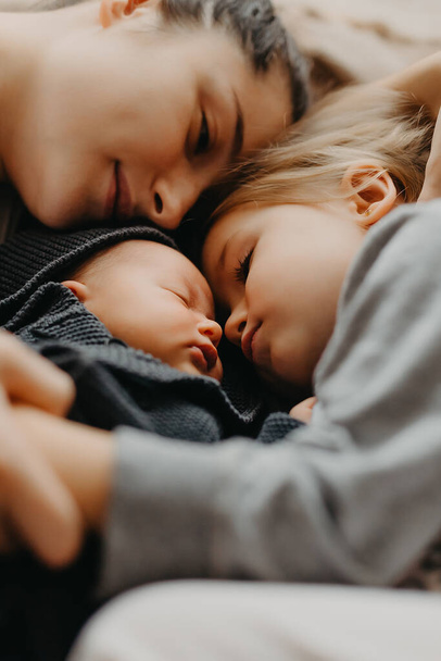 the mother lay down to sleep next to her daughters. Home photo of children with mom who fell asleep hugging - Foto, Imagem