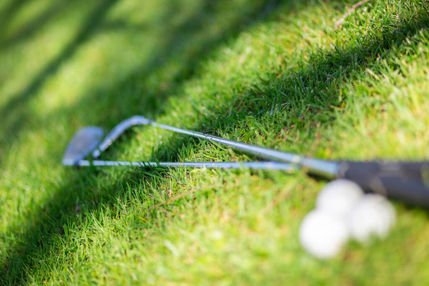 Hintergrund mit verschwommenen Golfschlägern und Bällen. Selektiver Fokus auf Gras. Konzept von Sport, Golf, Entspannung, Urlaub oder Ruhe. - Foto, Bild