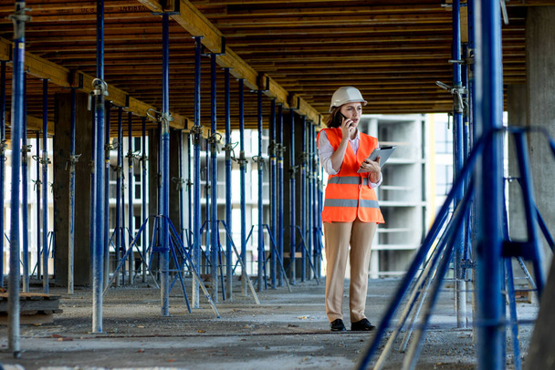Female construction engineer. Architect with a tablet computer at a construction site. Young Woman looking, building site place on background. Construction concept - Foto, imagen