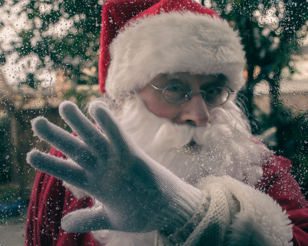 Санта Клаус вытирает мокрые окна. - Фото, изображение