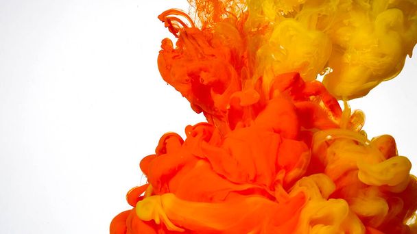 Colored cloud of ink on a white background. Yellow and orange watercolor ink in water on a white background. Abstract background. Yellow and orange paints are mixed in water. - Photo, image