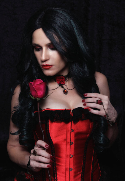 Nainen punaisessa korsetissa punaisella ruusulla - Valokuva, kuva