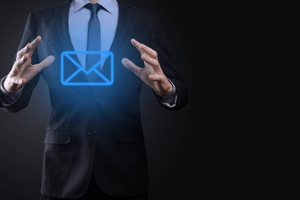 Businessman hand holding e-mail icon, Contact us by newsletter email and protect your personal information from spam mail. Customer service call center contact us concept. - Photo, Image