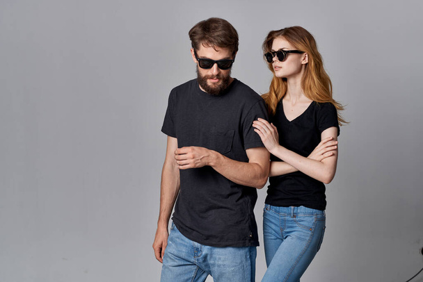 een jong paar in zwart t-shirt zonnebril poseren geïsoleerde achtergrond - Foto, afbeelding