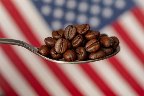 Une cuillère remplie de grains de café torréfiés sur le fond du drapeau de l'Amérique. Concept : exportation et importation de grains de café, livraison de biens, consommation. - Photo, image