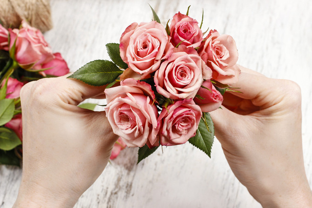 Florist at work. Woman making bouquet of pink roses - Photo, Image