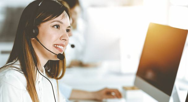 Asian woman working at customer service office. Business concept. Group of diverse operators at work in sunny call center. - Φωτογραφία, εικόνα