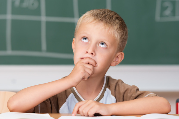 Little boy sitting thinking in class - Foto, afbeelding