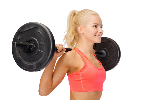 smiling sporty woman exercising with barbell - Valokuva, kuva
