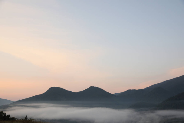 Picturesque view of mountains covered with fog in morning - Photo, image