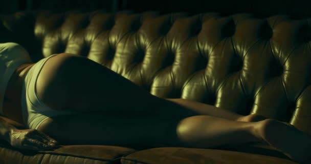 Замедленная съемка молодой очаровательной женщины, соблазнительно лежащей на диване в гостиной. - Кадры, видео