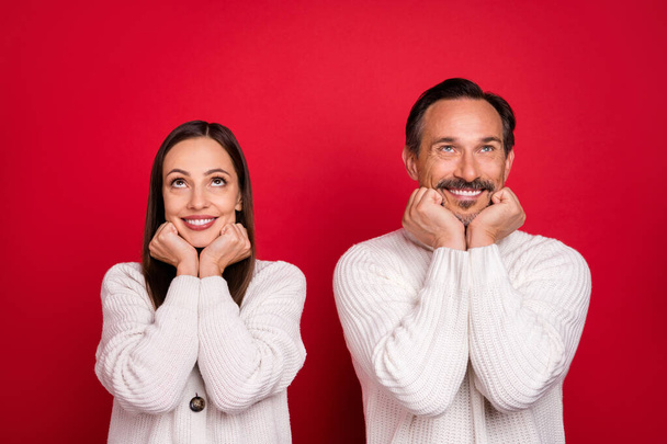 Photo of positive happy wife husband man and woman hold hands face look up empty space isolated on red color background - Foto, Bild