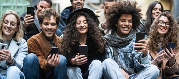 Jonge multiraciale groep vrienden met behulp van mobiele smartphone zitten op stedelijke trappen - Jeugd millennial lifestyle concept - Foto, afbeelding