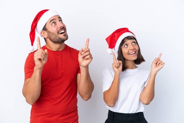 Young couple with christmas hat isolated on white background pointing with the index finger a great idea - Foto, Imagem