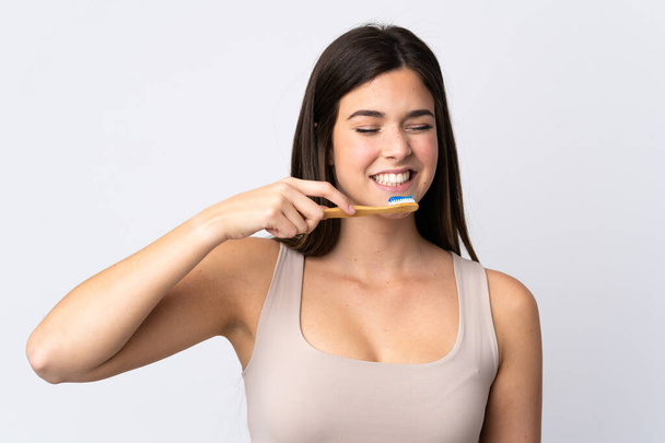 Teenager Brazilian girl brushing her teeth over isolated white background - Фото, изображение