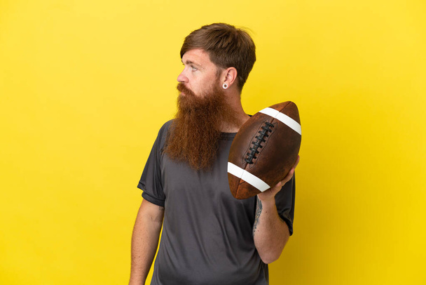 Redhead caucasian man playing rugby isolated on yellow background  - Photo, Image
