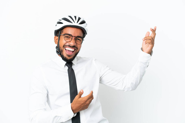 Joven hombre latino de negocios sosteniendo un casco de bicicleta aislado sobre fondo blanco haciendo gesto de guitarra - Foto, imagen