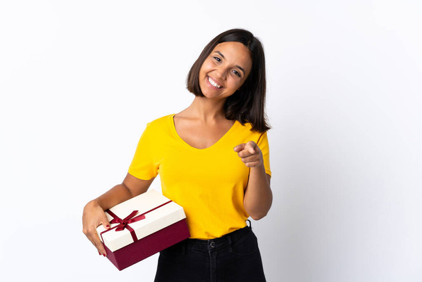Young latin woman holding a gift isolated on white background pointing front with happy expression - Foto, Bild