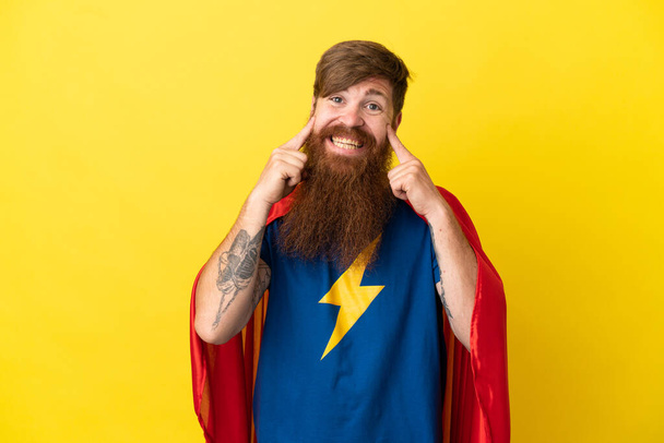 Redhead Super Hero man isolated on yellow background smiling with a happy and pleasant expression - Photo, Image