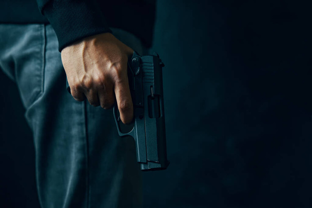 Crimineel met revolver op donkere achtergrond. - Foto, afbeelding