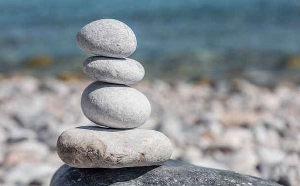 Ισορροπία, zen πέτρες, ομαλή πυραμίδα πέτρα στοιβάζονται σε παραλία βότσαλο, μπλε φόντο της θάλασσας, ηλιόλουστη μέρα. Φενγκ σούι, αρμονία και ειρήνη έννοια. Αντιγραφή χώρου, πρότυπο. - Φωτογραφία, εικόνα