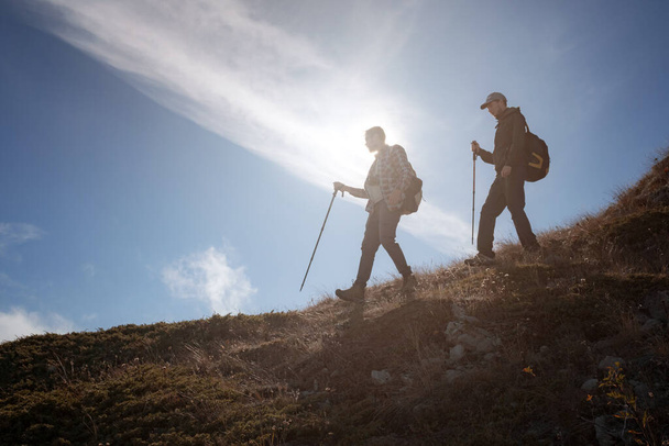 Two men silhouettes walking along the top of the mountain - Photo, Image