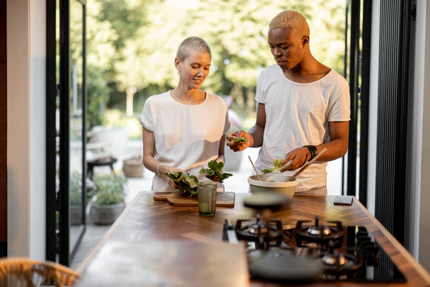 Multiracial pareja cocina ensalada en casa cocina - Foto, imagen