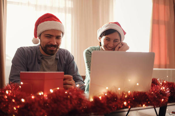 Счастливая молодая пара использует или смотрит что-то на ноутбуке на Новый год - Фото, изображение