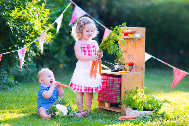 Kleine Kinder spielen mit Spielzeugküche im Garten - Foto, Bild