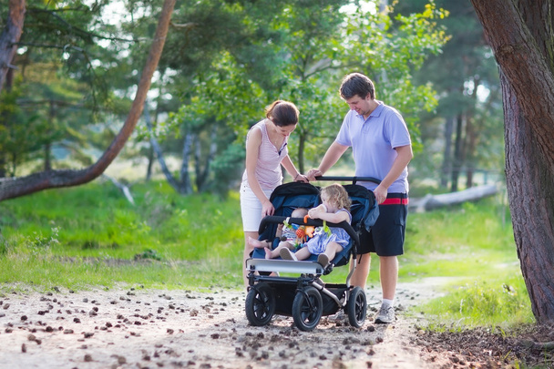 Молоді сімейні пішохідні тури з двома дітьми в колясці
 - Фото, зображення