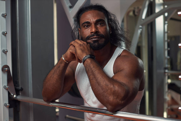 a black muscular man in a narrow white T-shirt stands at the gym - Foto, Imagem