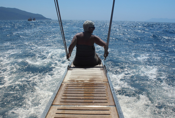Жінка сидить на задній частині моторного човна
 - Фото, зображення
