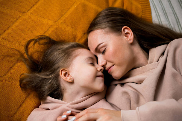 mamá y su hija están acostadas en una manta en la cama y abrazándose - Foto, imagen