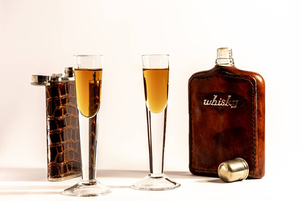 zwei Beutel zur Aufbewahrung allgemein alkoholischer Getränke und zwei Gläser mit einer gerösteten Flüssigkeit auf hellem Hintergrund - Foto, Bild