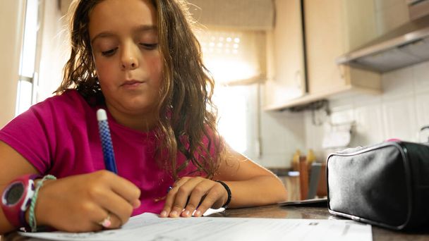 dívka s dlouhými vlasy dělat školní práci psaní odpovědí do notebooku - Fotografie, Obrázek