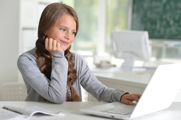 schoolgirl doing home work with laptop  in the room  - Photo, image