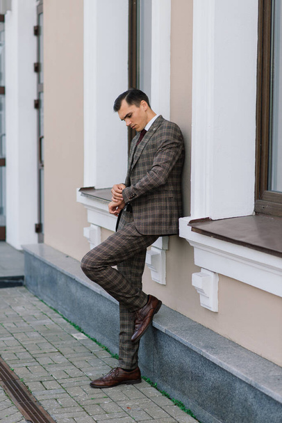 Portré egy vonzó fiatal üzletemberről városi háttérben öltönyben és nyakkendőben.. - Fotó, kép