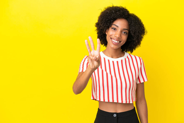 Young African American woman isolated on yellow background happy and counting three with fingers - Photo, Image